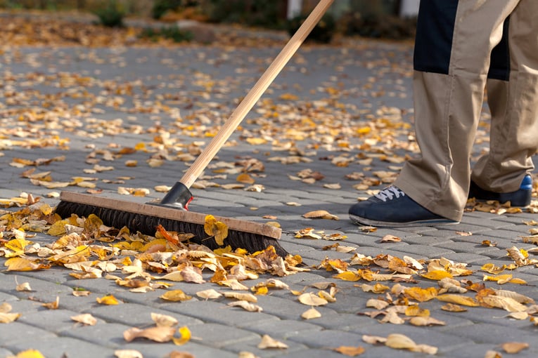 Worker cleaning up the driveway from autumn leaves