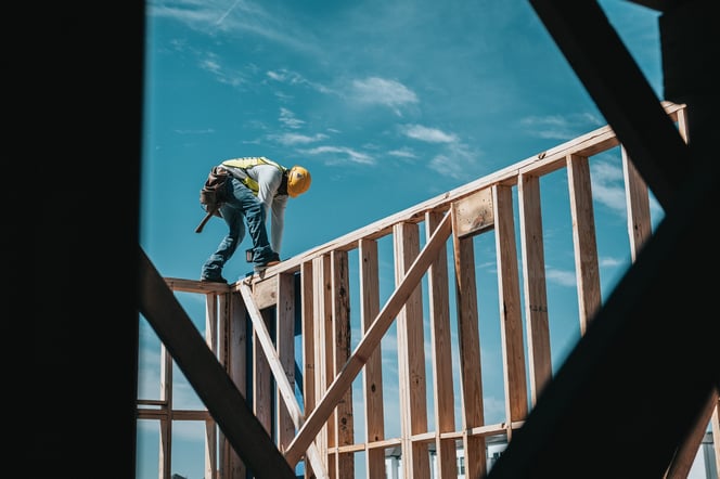 man-working-wood-framed-house